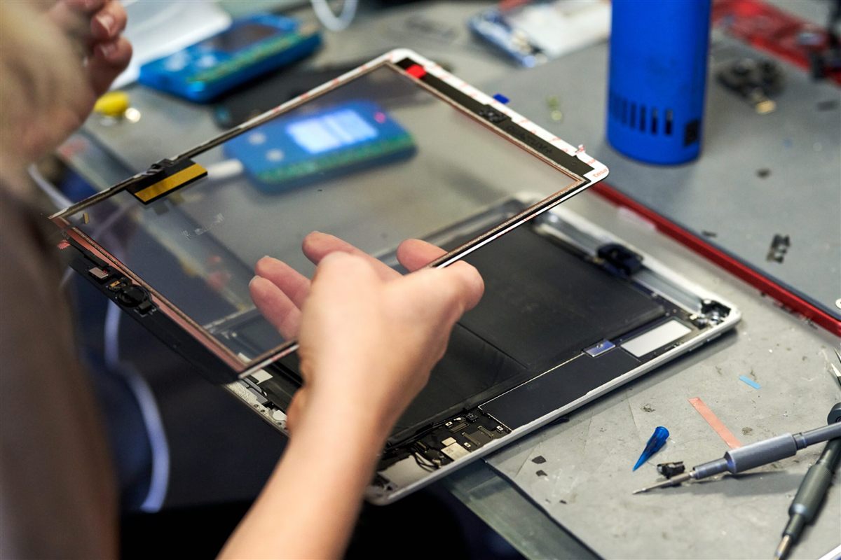 Technician replacing a cracked iPad screen on a repair bench in Boca Raton